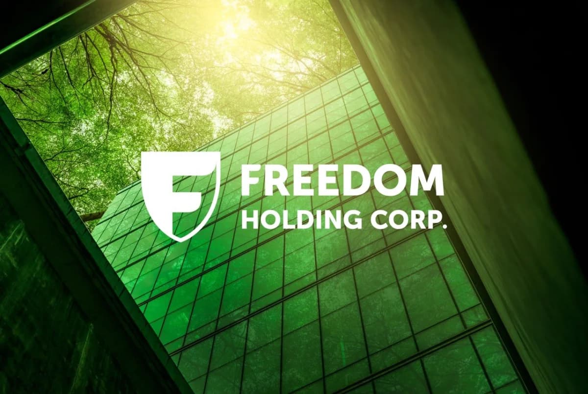 Логотип Freedom Holding Corp на фоне зелёного стеклянного небоскрёба с солнечным светом и зелёными кронами деревьев сверху, метафора цифровой экосистемы Freedom SuperApp в Казахстане в 2026 году